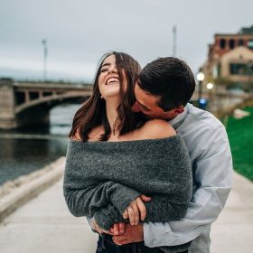 Romantic engagement moment captured along the Riverwalk Promenade in Grand Rapids