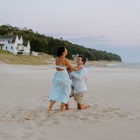 oval-beach-saugatuck-engagement-photo.jpg Couple proposing on the sandy shore of Oval Beach in Saugatuck, MI